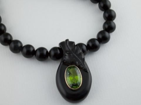 Jet carved with a vine leaf and housing an 18ct Gold bezel and Peridot