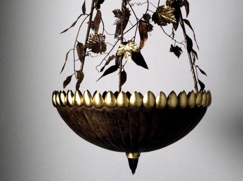 Copper bowl with gum and vine leaves. The uplight scatters leaves on the ceiling.