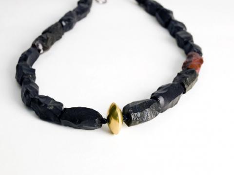 Meteorite originating in outer space is a gift from another world with a gold central bead.
